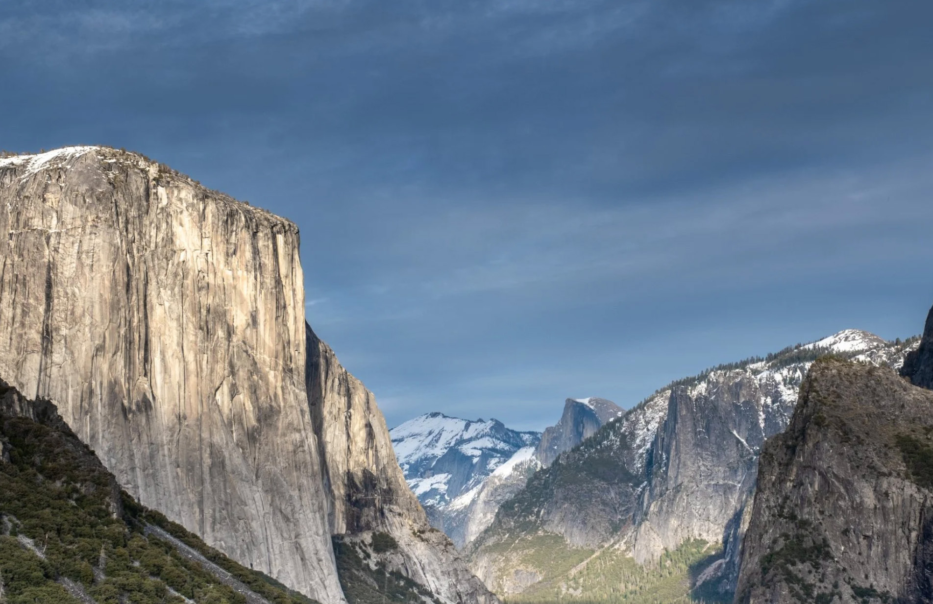Yosemite Valley, El Capitan rising above forest with snow-covered peaks beyond